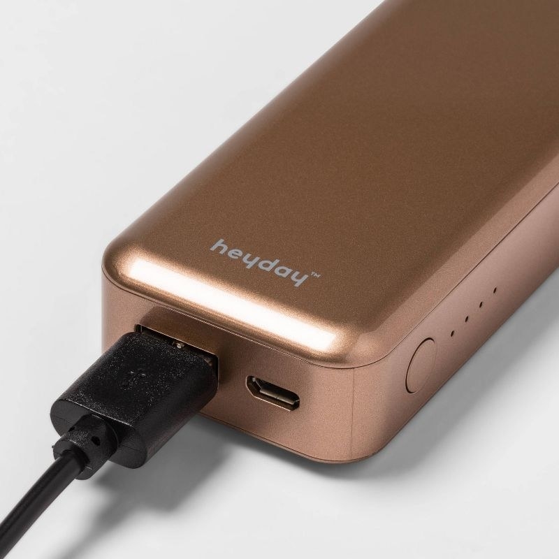 A rose gold phone charger with a black cord in it