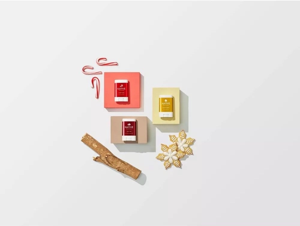 A orange, a red and yellow deodorant with a stick, sugar cookies and candy canes