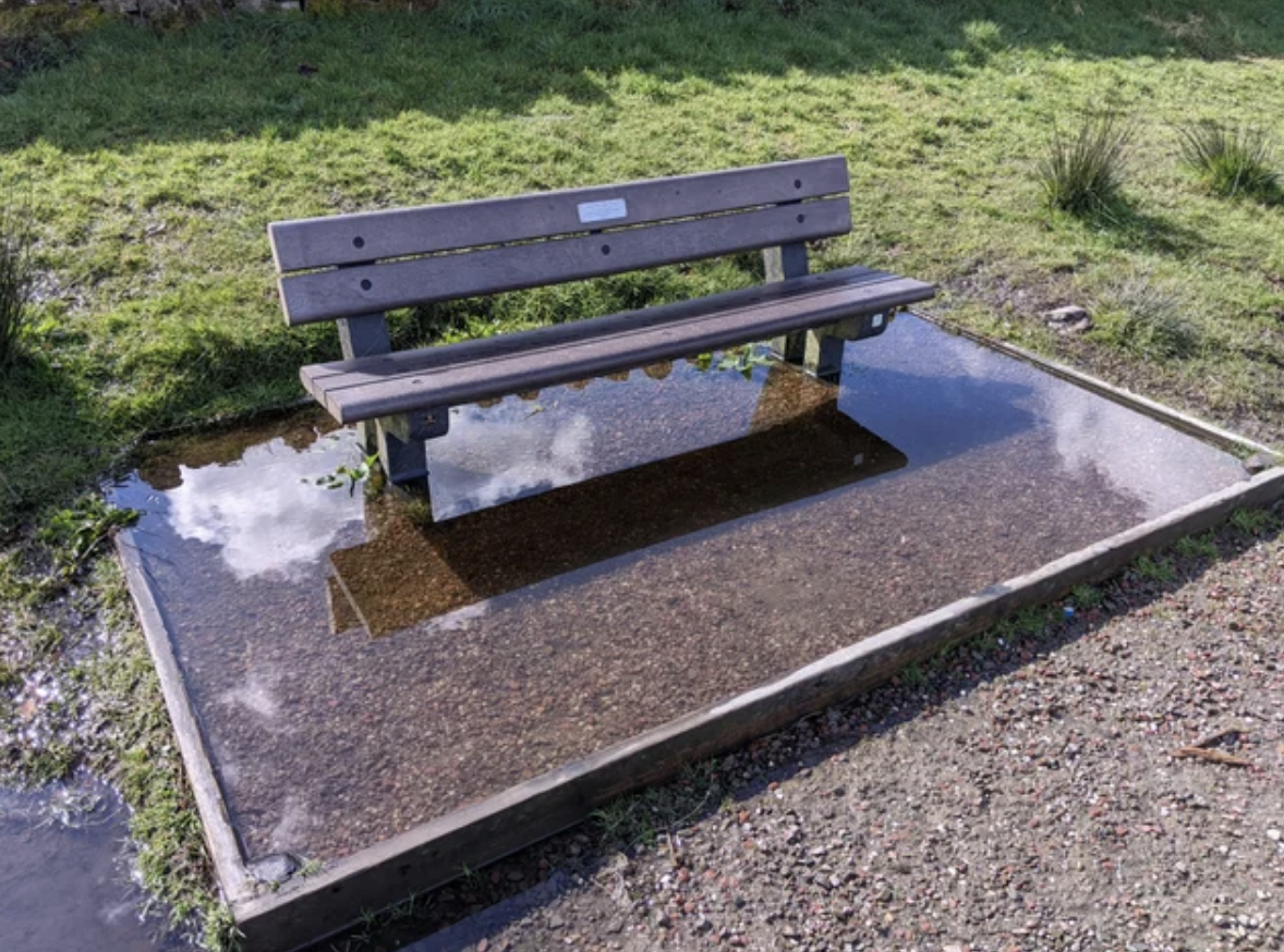 A bench surrounded by a puddle