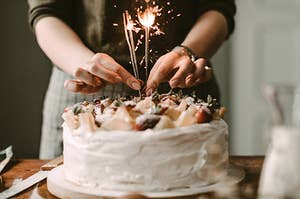 Two sparklers sit on a fruit topped cake