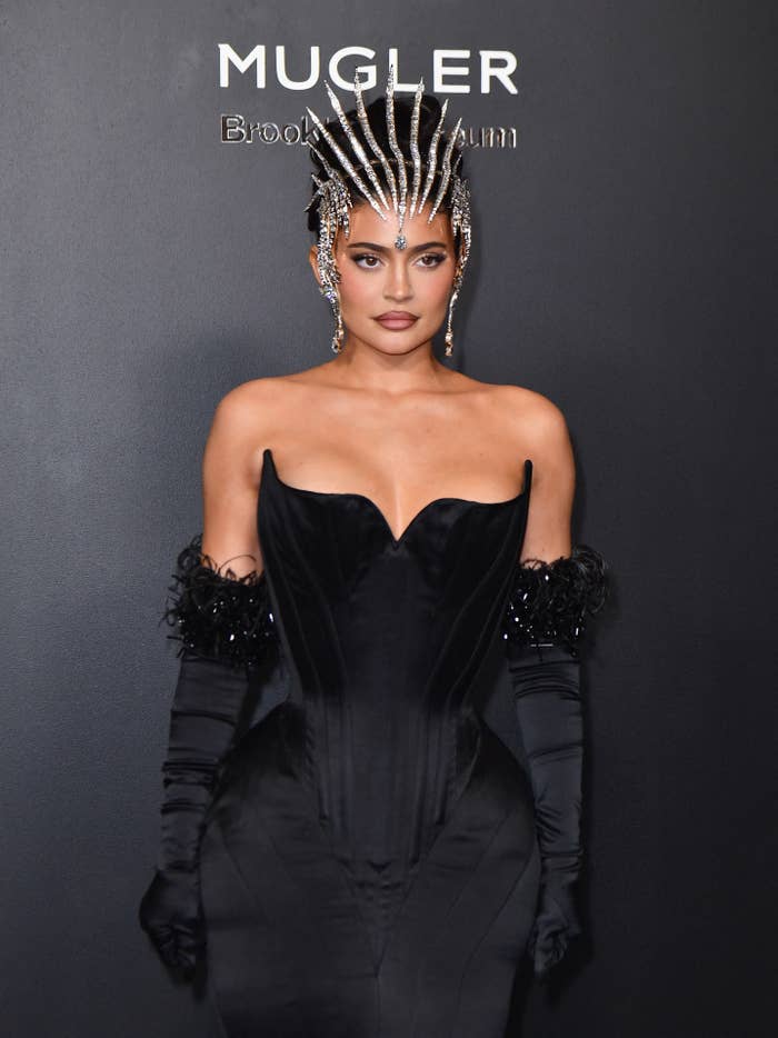 Kylie at a red carpet event wearing a strapless sweetheart neckline dress with opera gloves and a jeweled headpiece