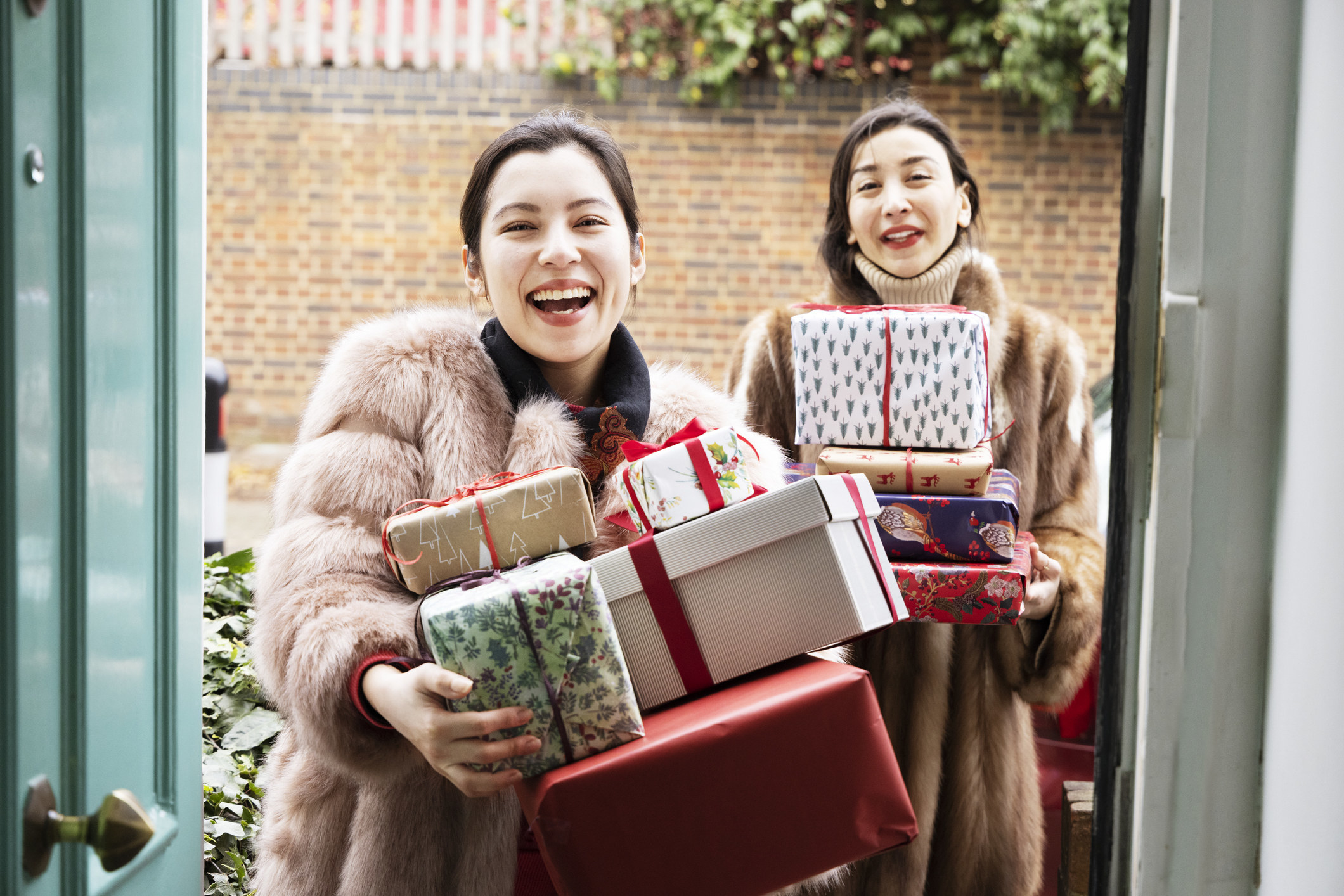 Two friends at the door with presents in their hands
