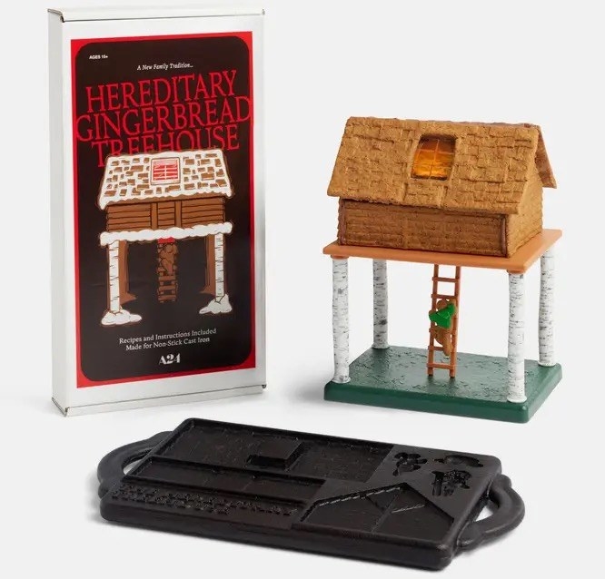 A gingerbread house on 4 birch tree legs with a person climbing up into it and the cast iron molds to make it