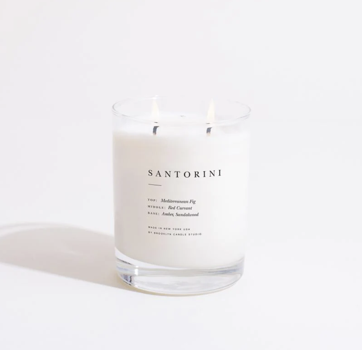 White candle with double wick in clear glass jar