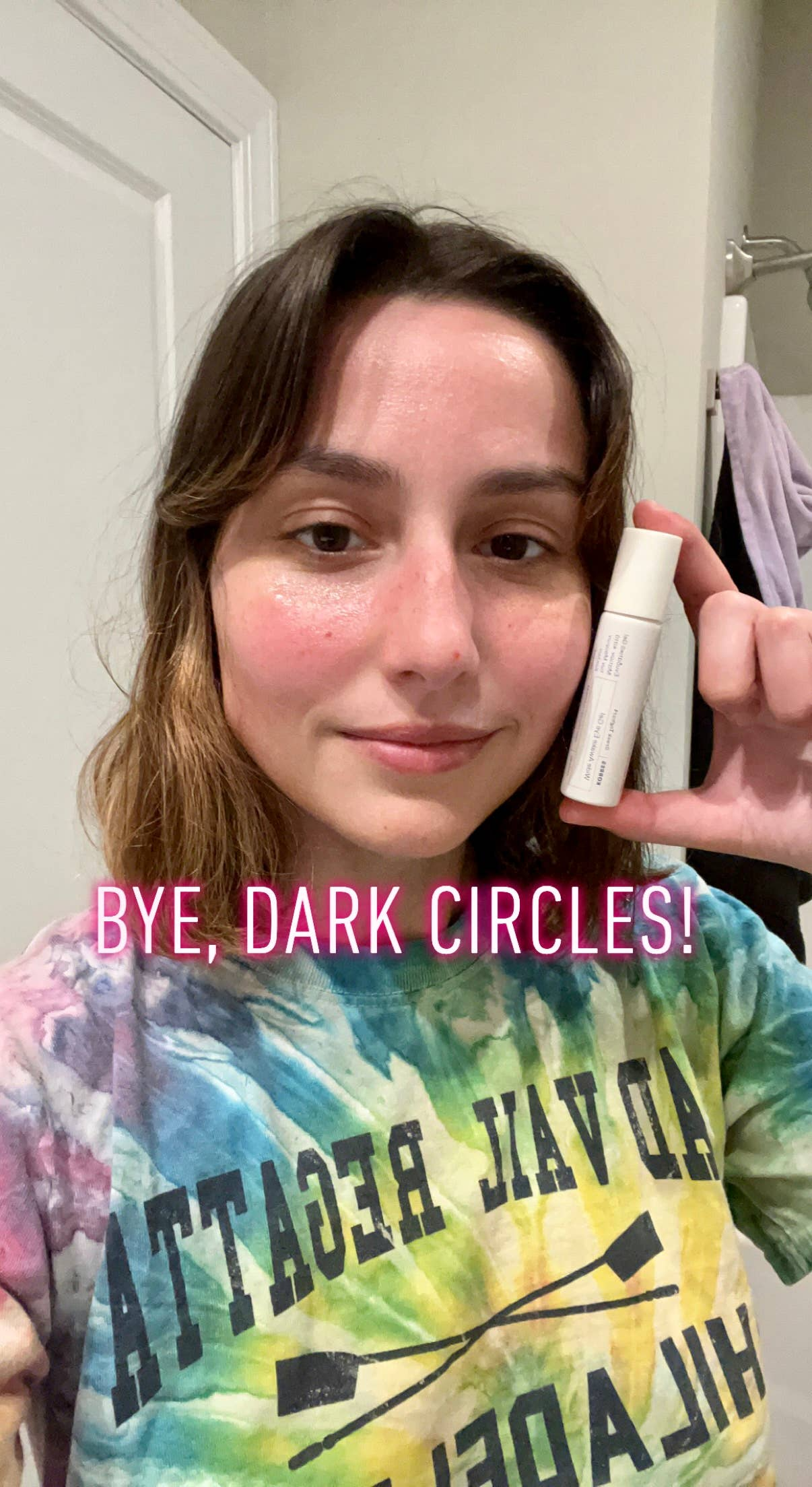 me, holding the eye gel roller ball next to my face, which has less dark circles