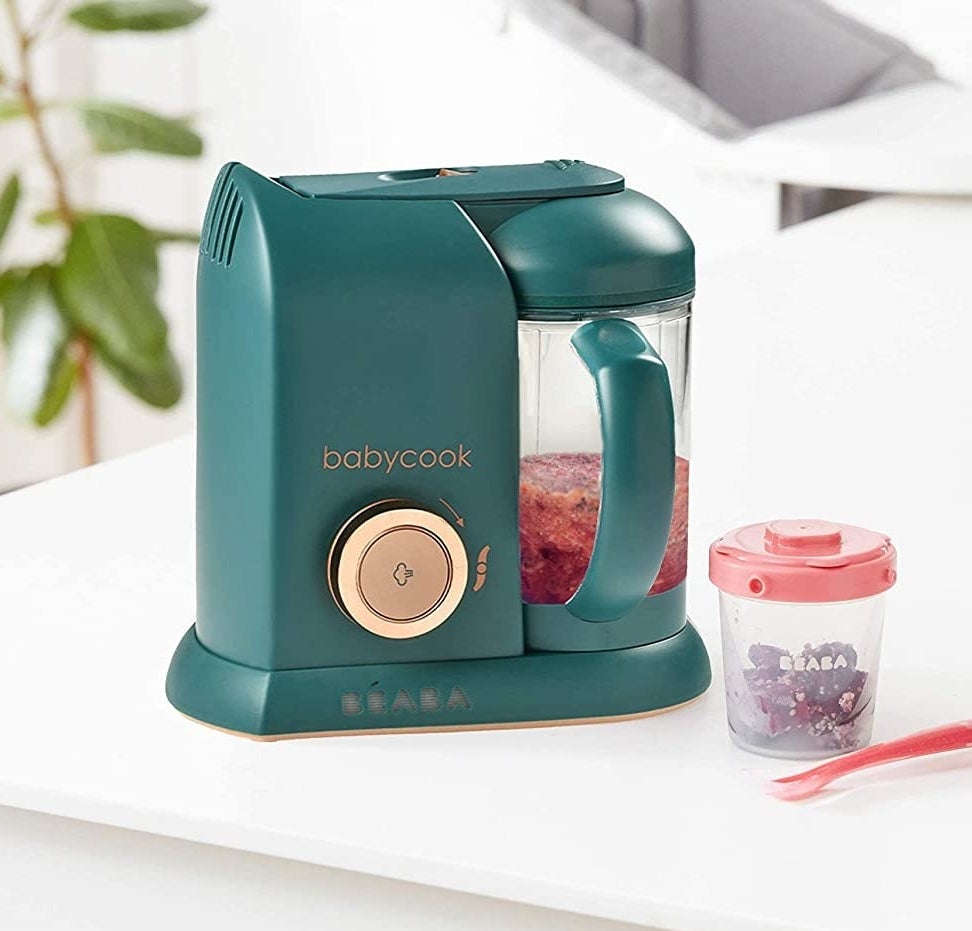 The baby food processor on a counter next to a cup and spoon