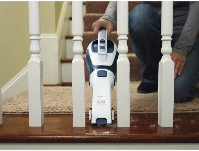 A person using the vacuum to clean fluffs in a stairwell