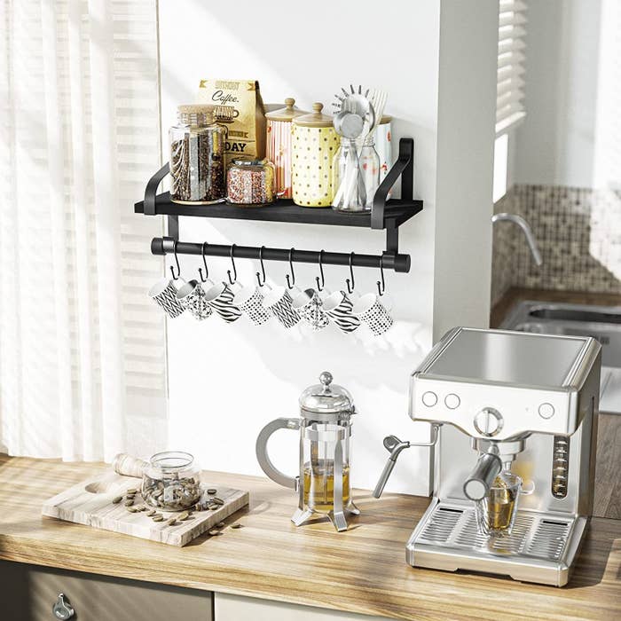 the shelf on a wall with some coffee and tea items and mugs hanging from it