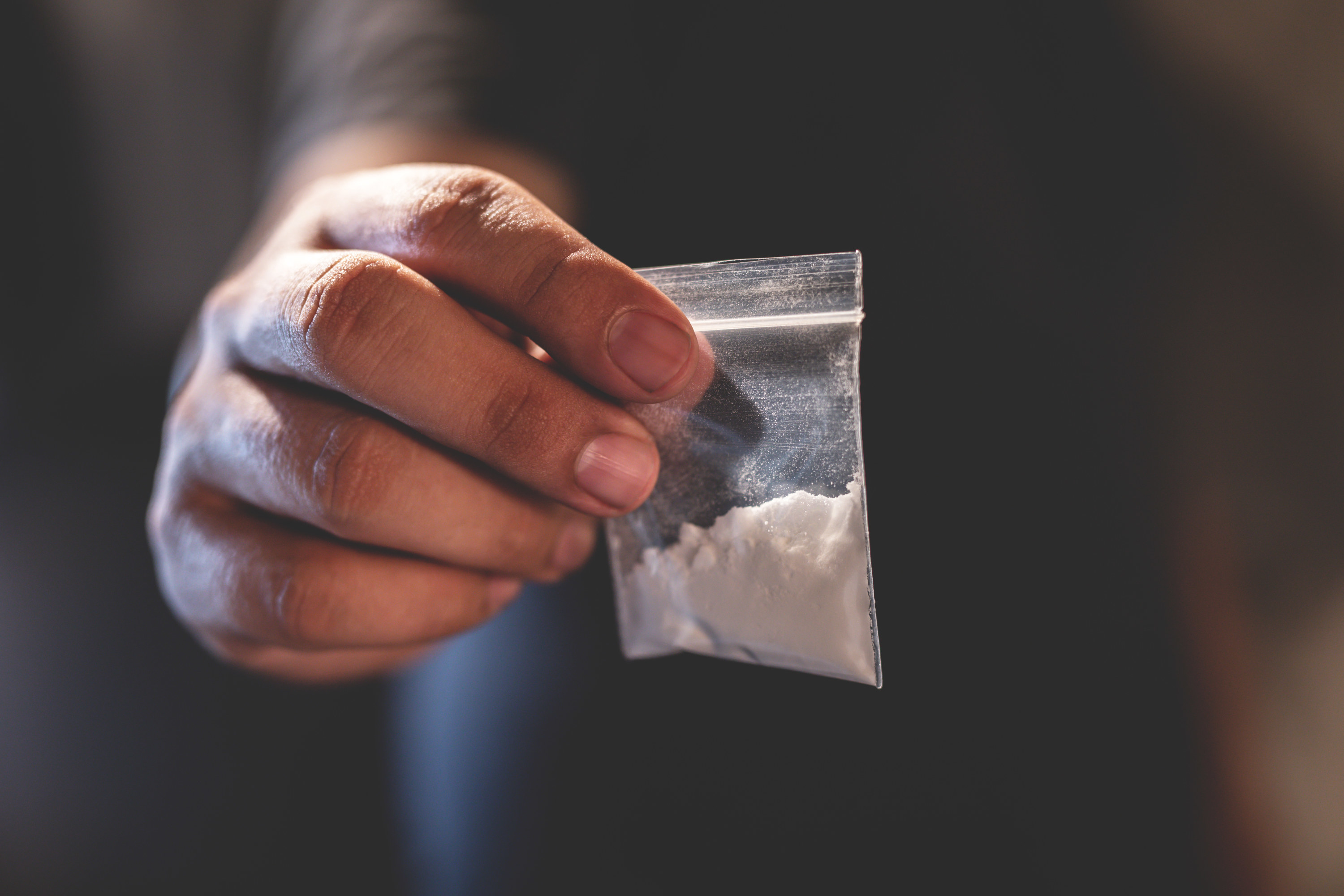 A hand holding a little baggie of cocaine