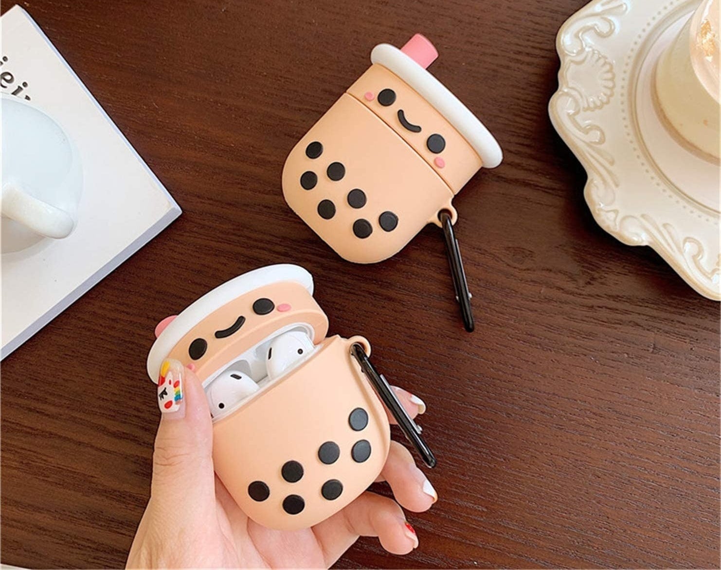 hand holding white AirPods stashed in cute Boba-shaped AirPods case