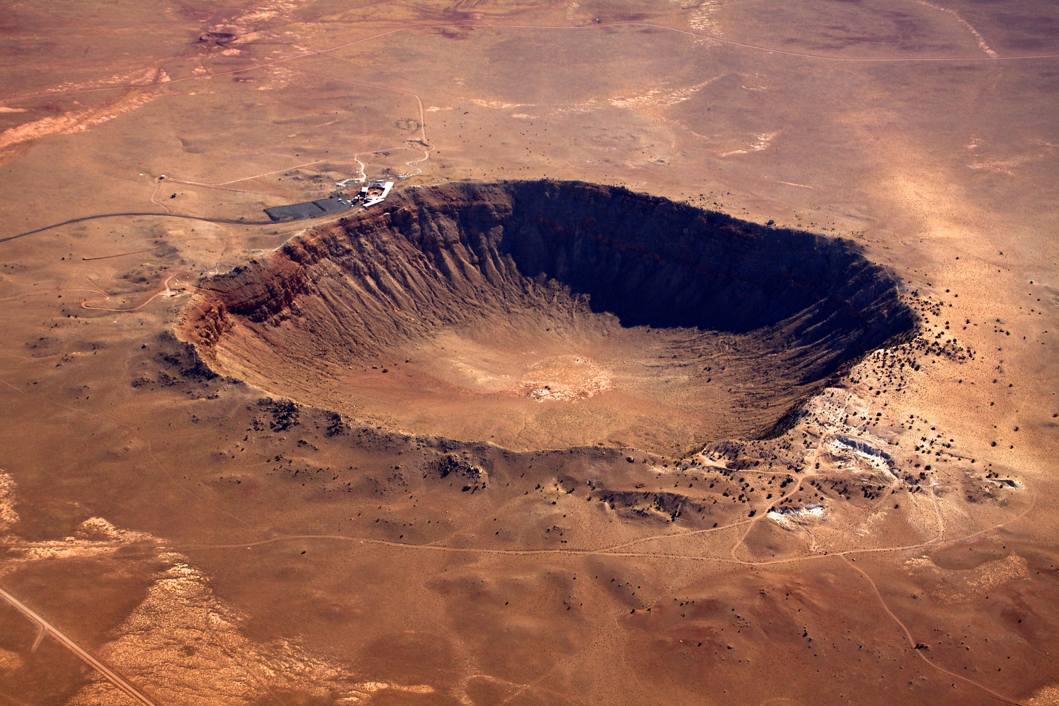 An enormous hole in a sandy, desertlike landscape