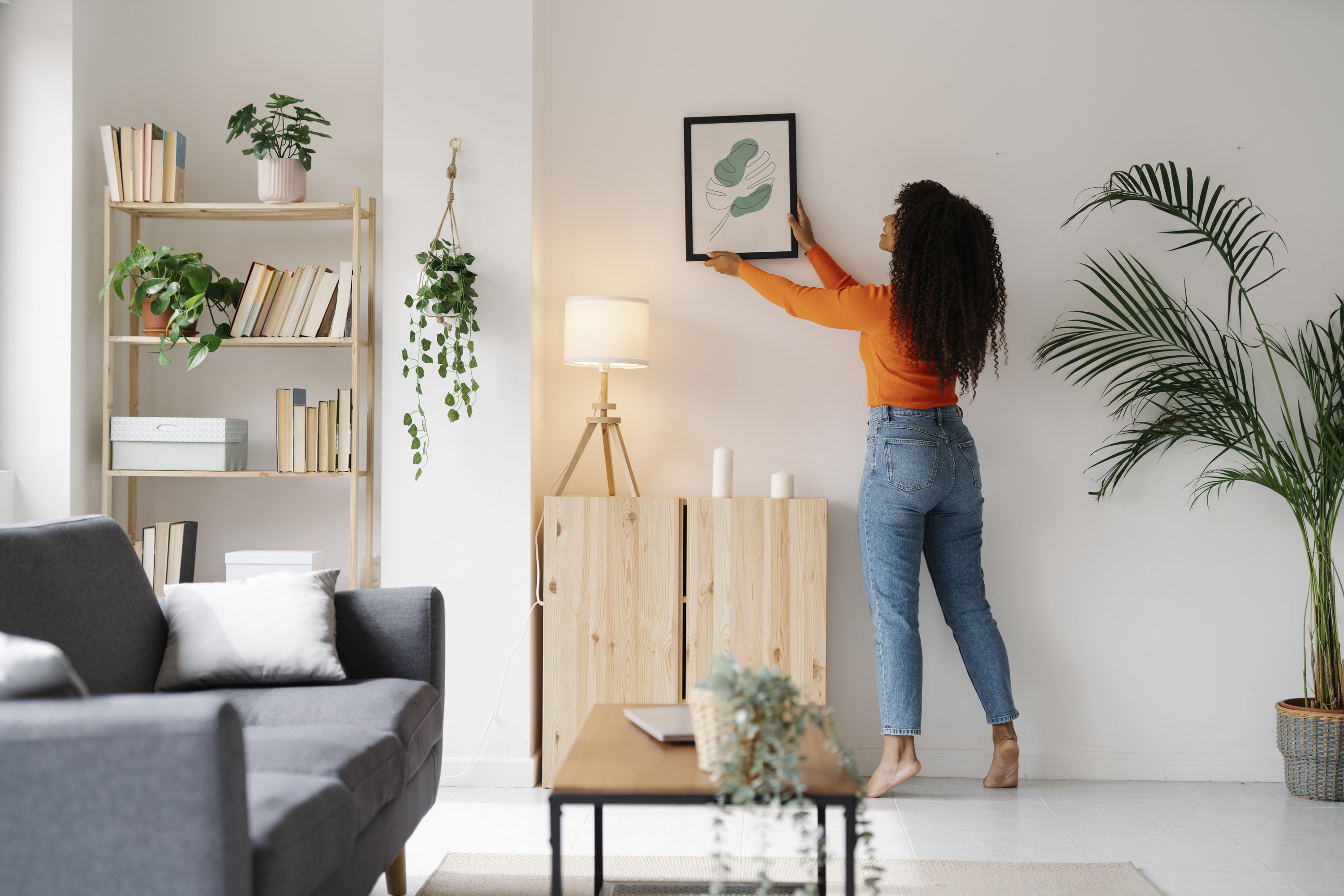 A woman hanging a framed picture
