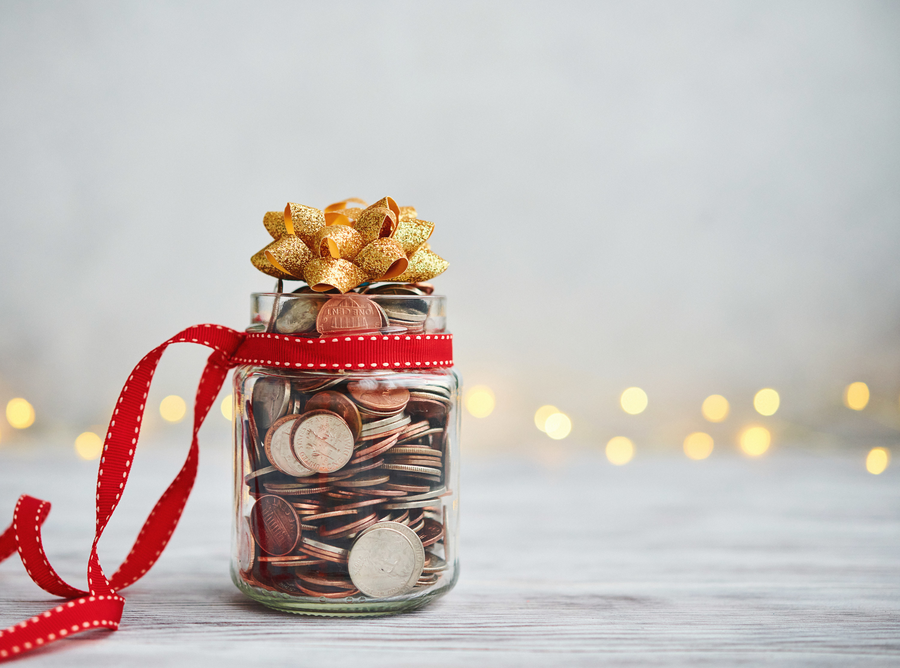 holiday savings jar filled with coins and decorated with a bow