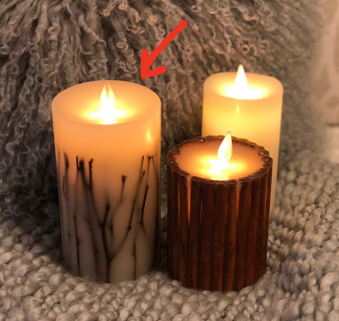 Three flameless candles with sticks on them glowing on top of yarn