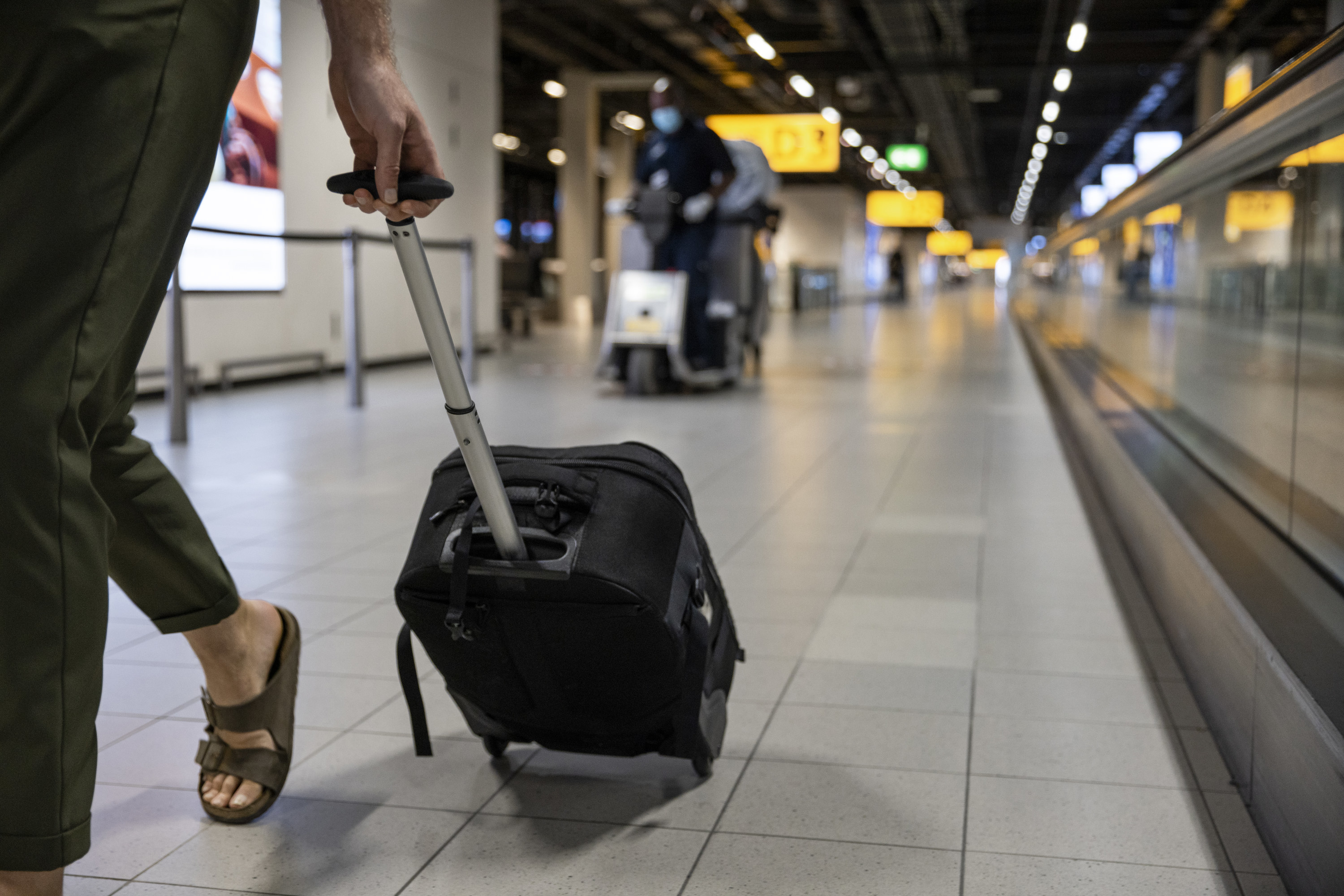person rolling suitcase through airport