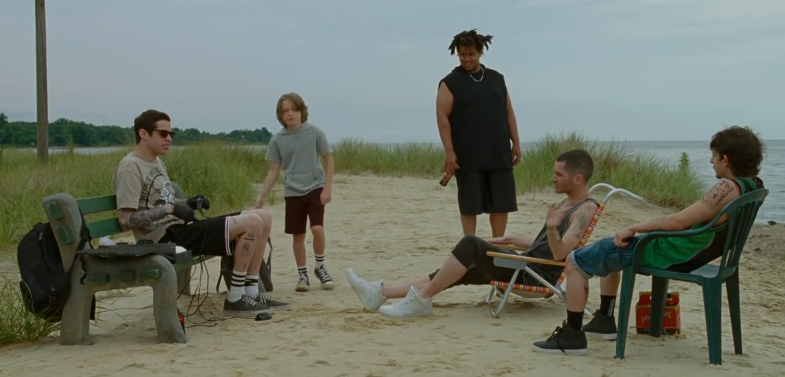 pete davidson, a child, and other castmates on the beach in &quot;the king of staten island&quot;