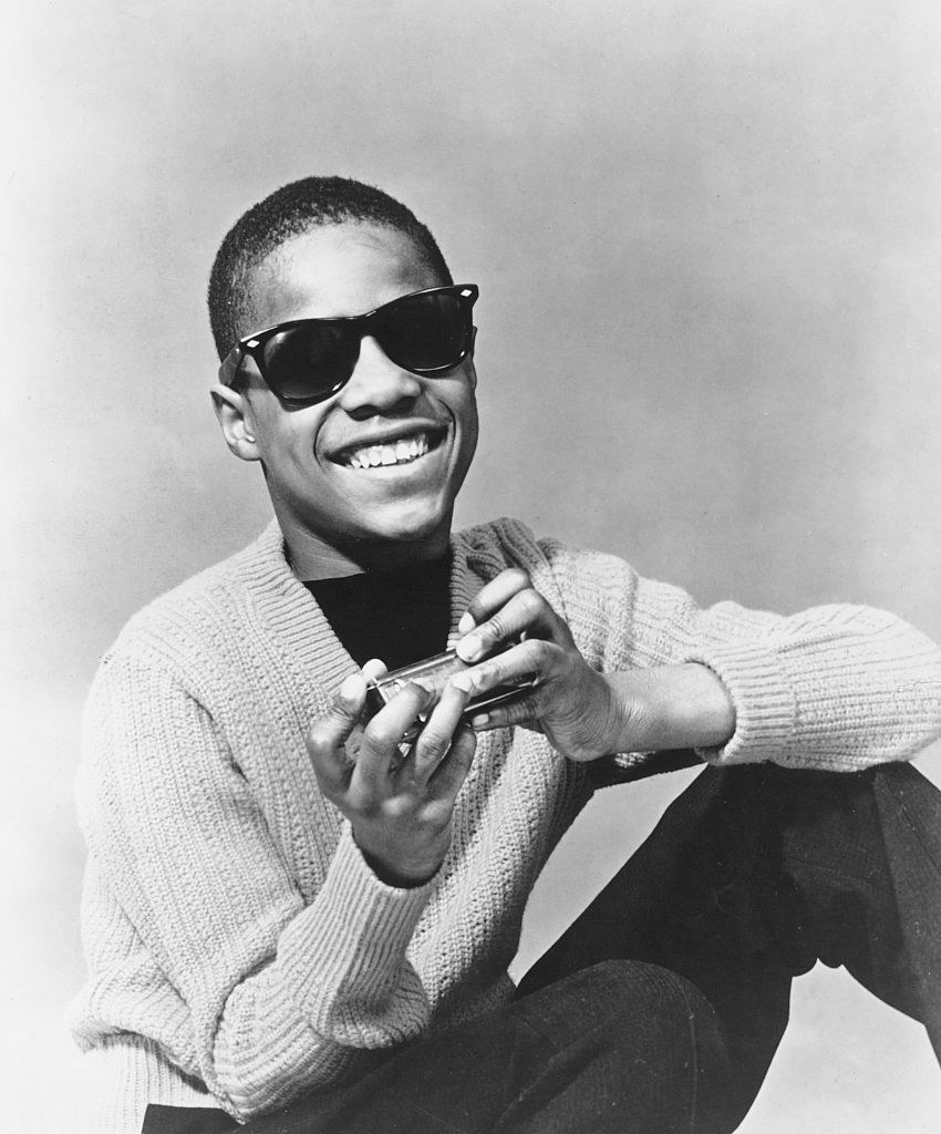 Stevie Wonder holding a harmonica and smiling