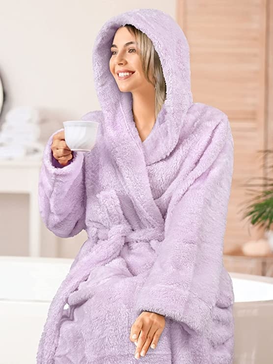 A picture of a woman wearing plush robe, holding a cup of tea