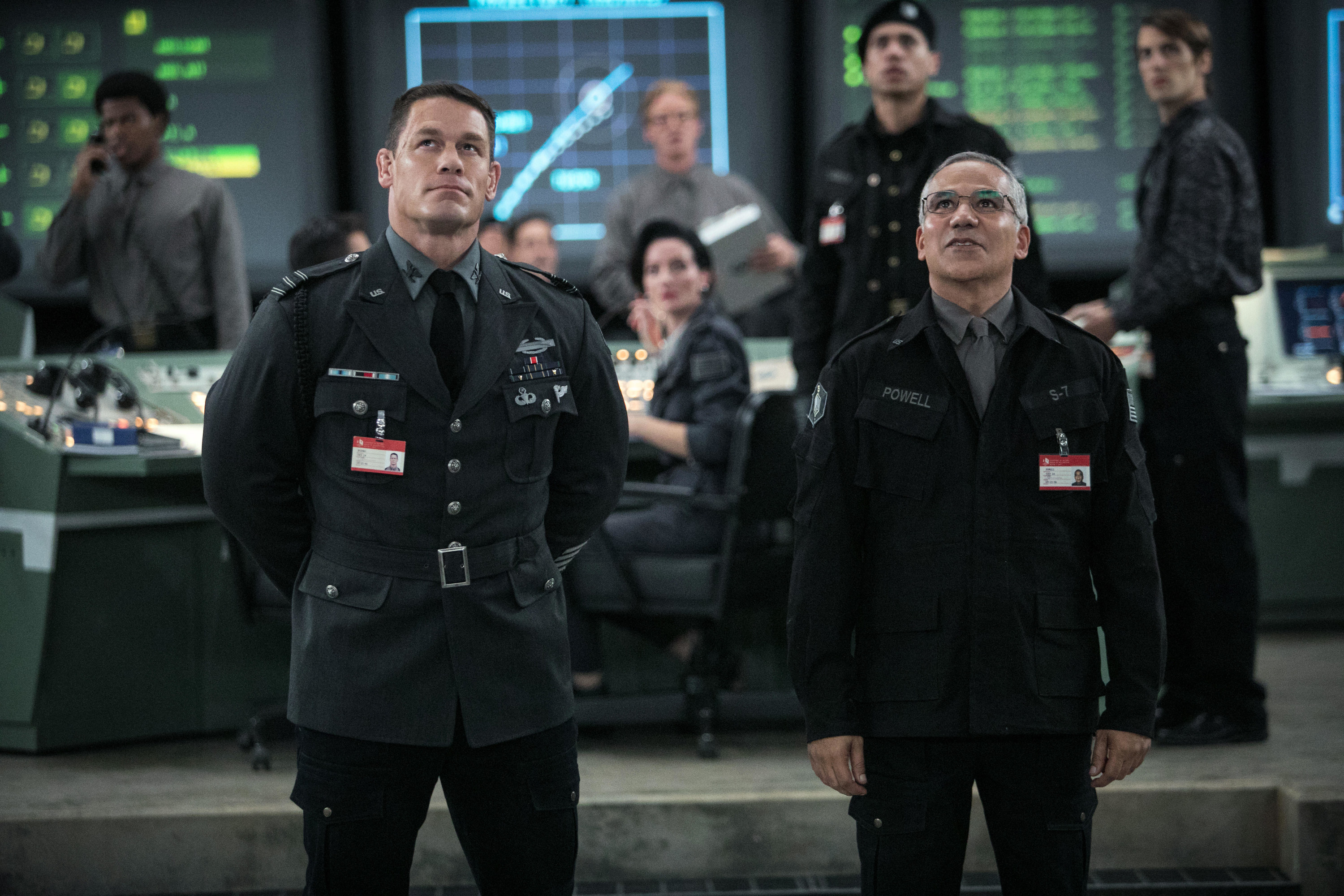 A general and a military scientist stare at a large screen in a futuristic war room