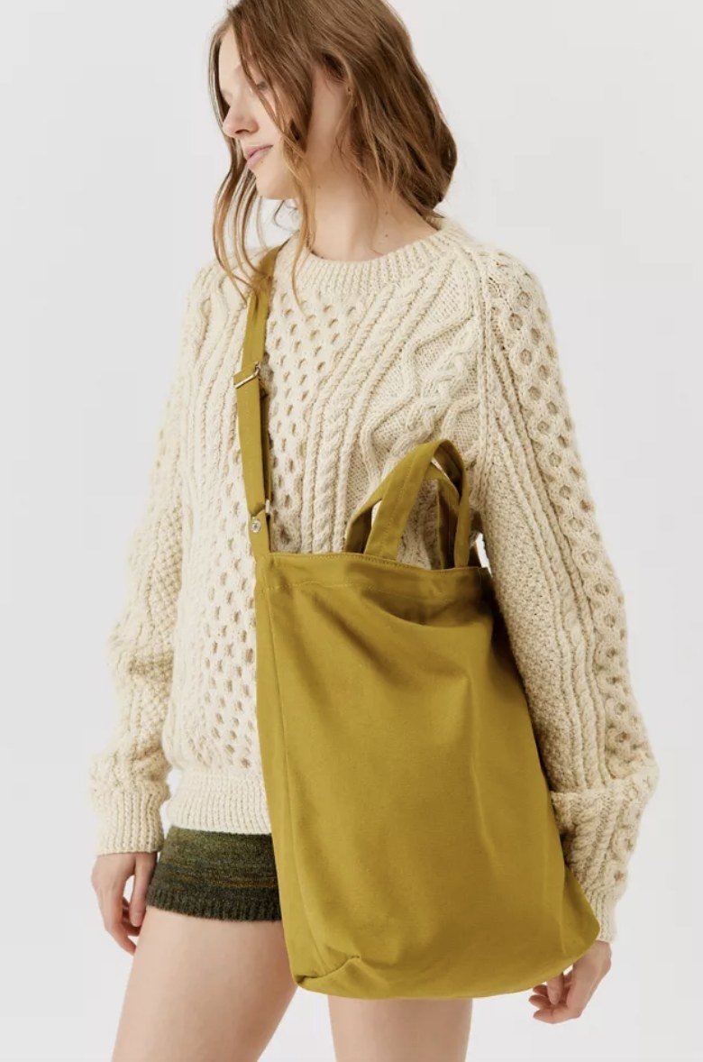The model carries the olive colored bag