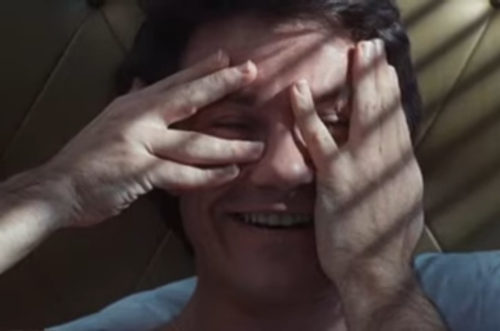 Harvey Keitel covers his eyes and smiles