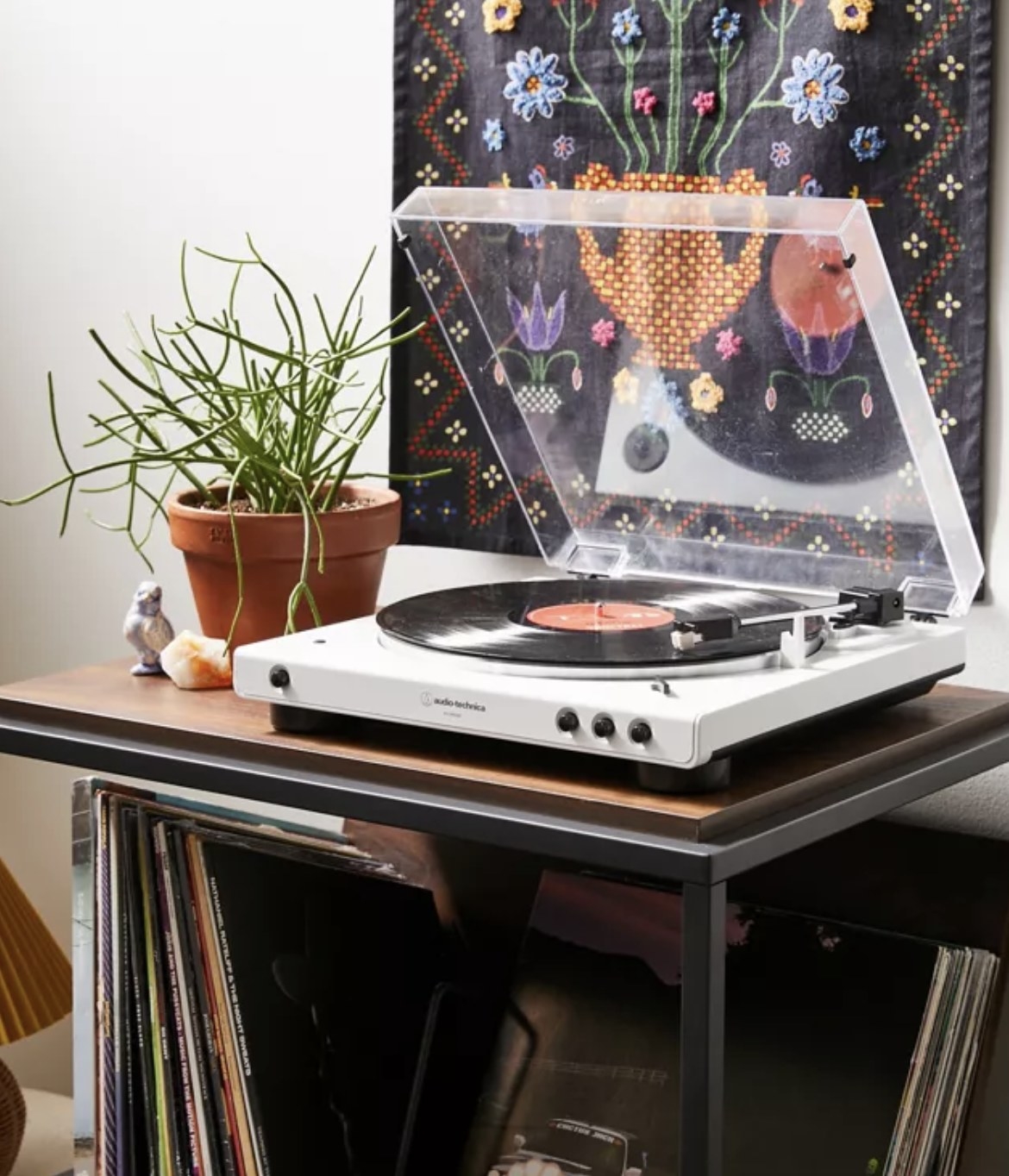 The record player is stacked on an organizer with records and other trinkets nearby