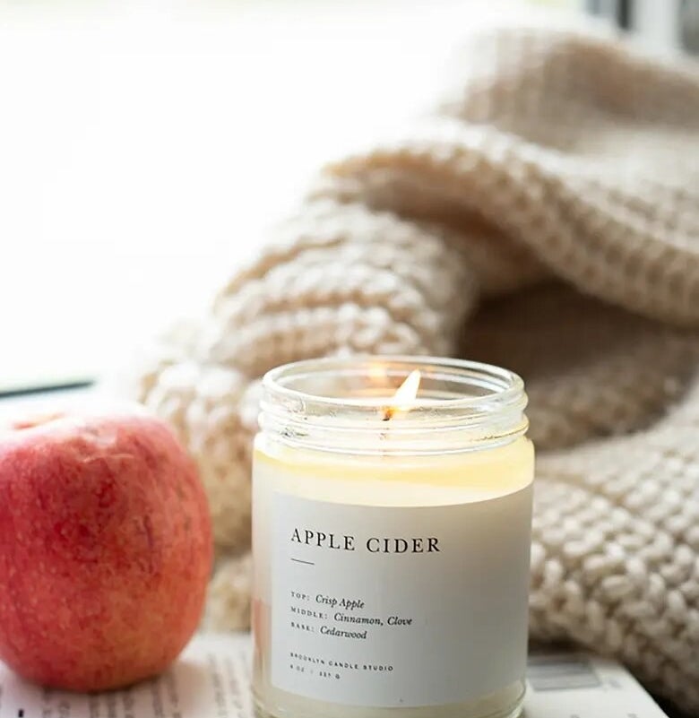 the candle on a book beside an apple and a blanket
