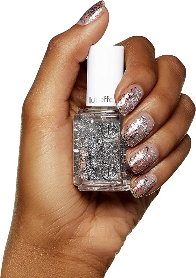 a person holding a nail polish with the sparkles on their nail