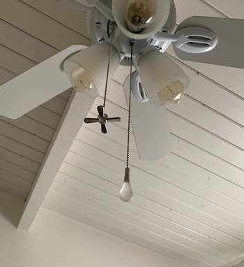 a ceiling fan with the fan and light bulb pulls hung from it
