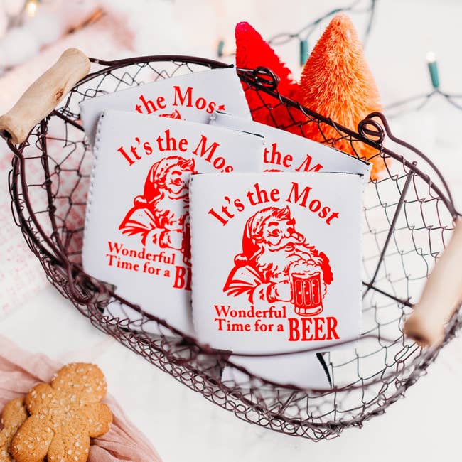 basket of white coozies with santa on it that says it's the most wonderful time for a beer