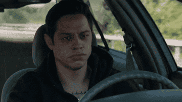 Pete Davidson driving and shutting his eyes tightly