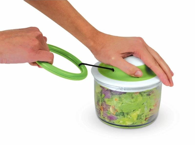 Hand holding vegetable cutter containing vegetables
