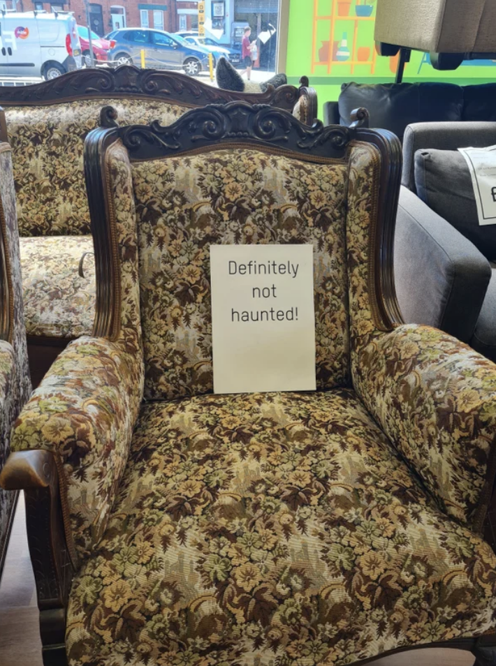 Sign on scary old-looking chair says, Definitely not haunted