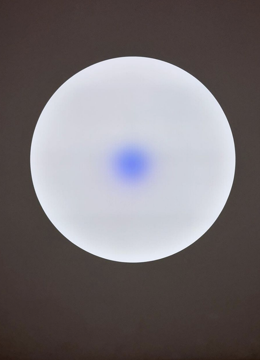 A circle of dim light with a small orb of blue light in the center