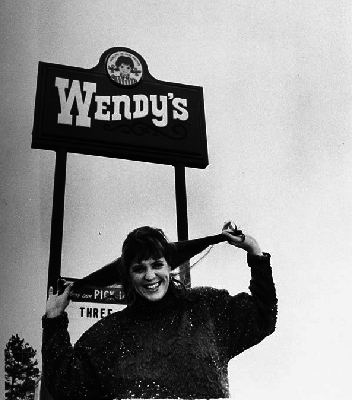 woman pulling her hair in two pigtails standing in front of the wendy&#x27;s sign