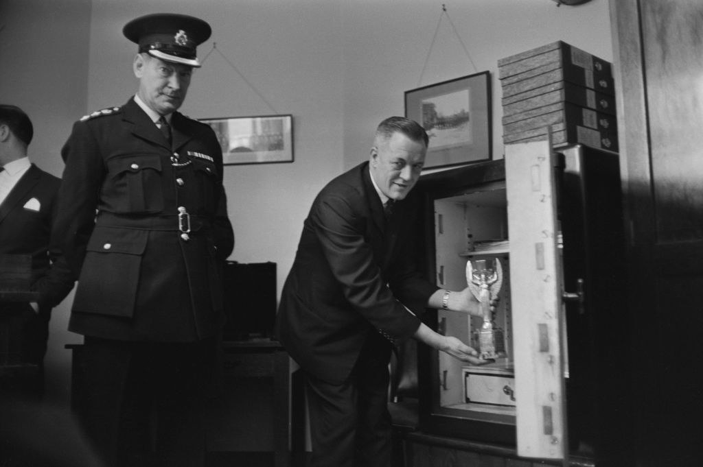 someone placing the trophy into a safety box while a policeman watches