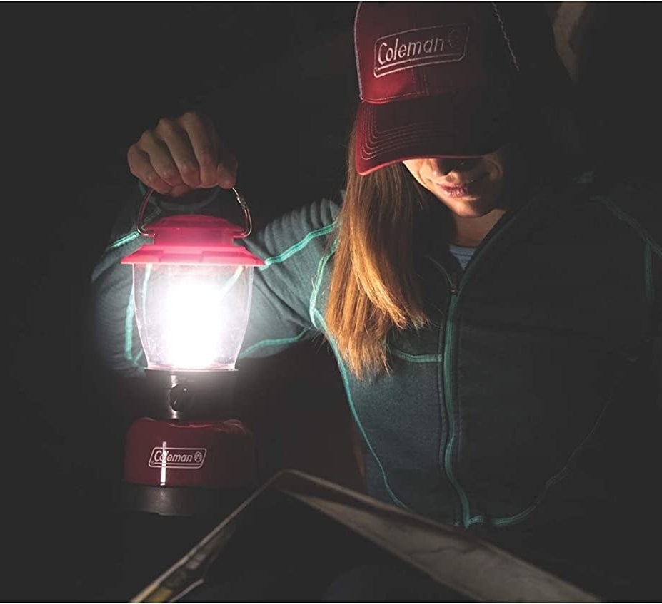 model holding red Coleman lantern by a handle