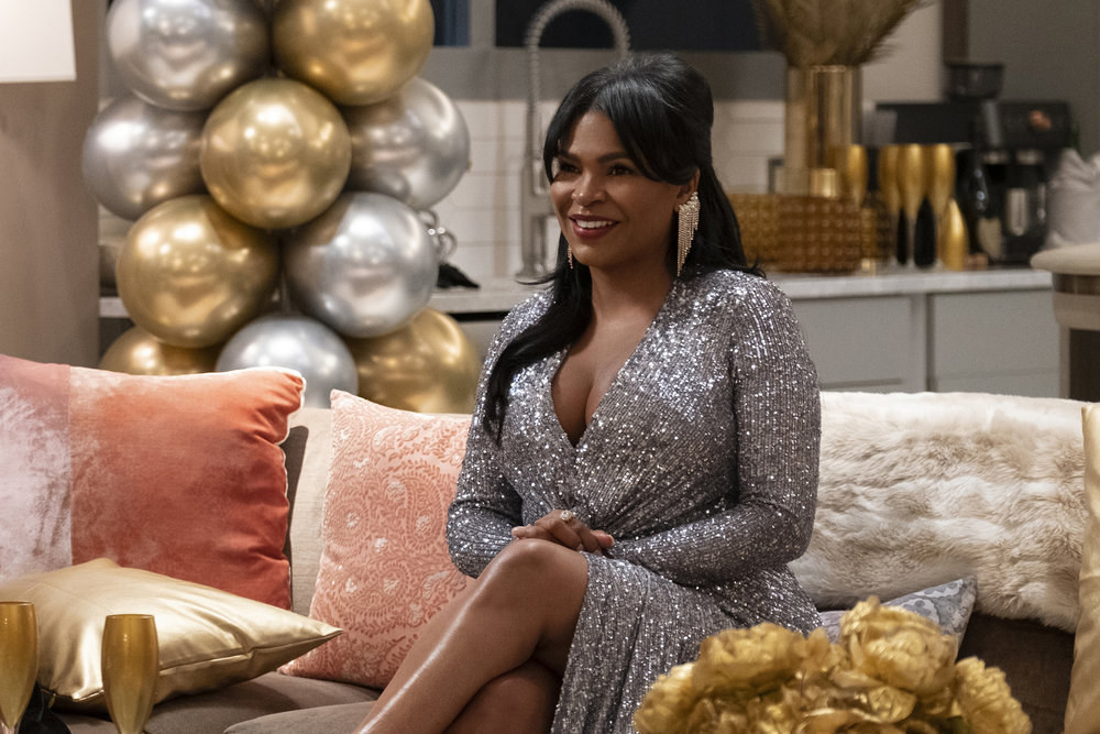 Nia Long sits on a couch