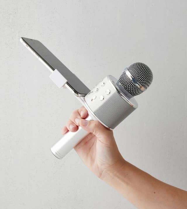 a person holding a microphone that has a phone sitting in its stand