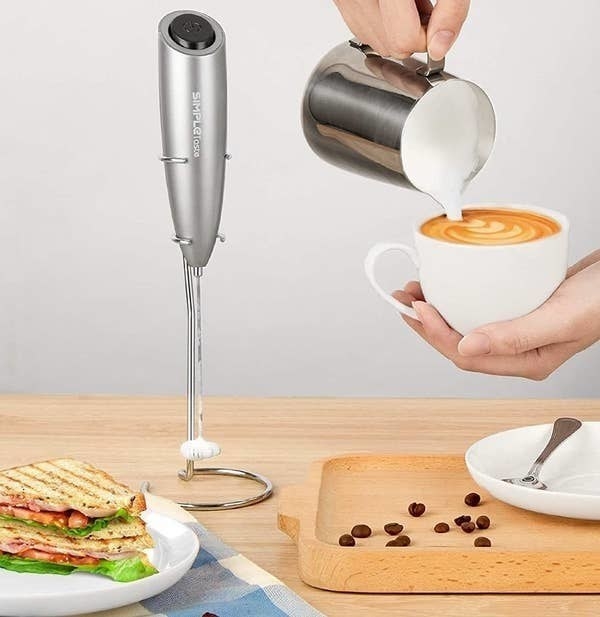 a person making a latte next to the frother