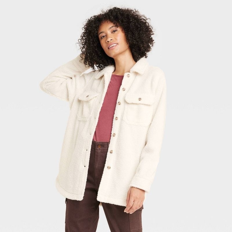 Model wearing white shacket with brown pants and pink top