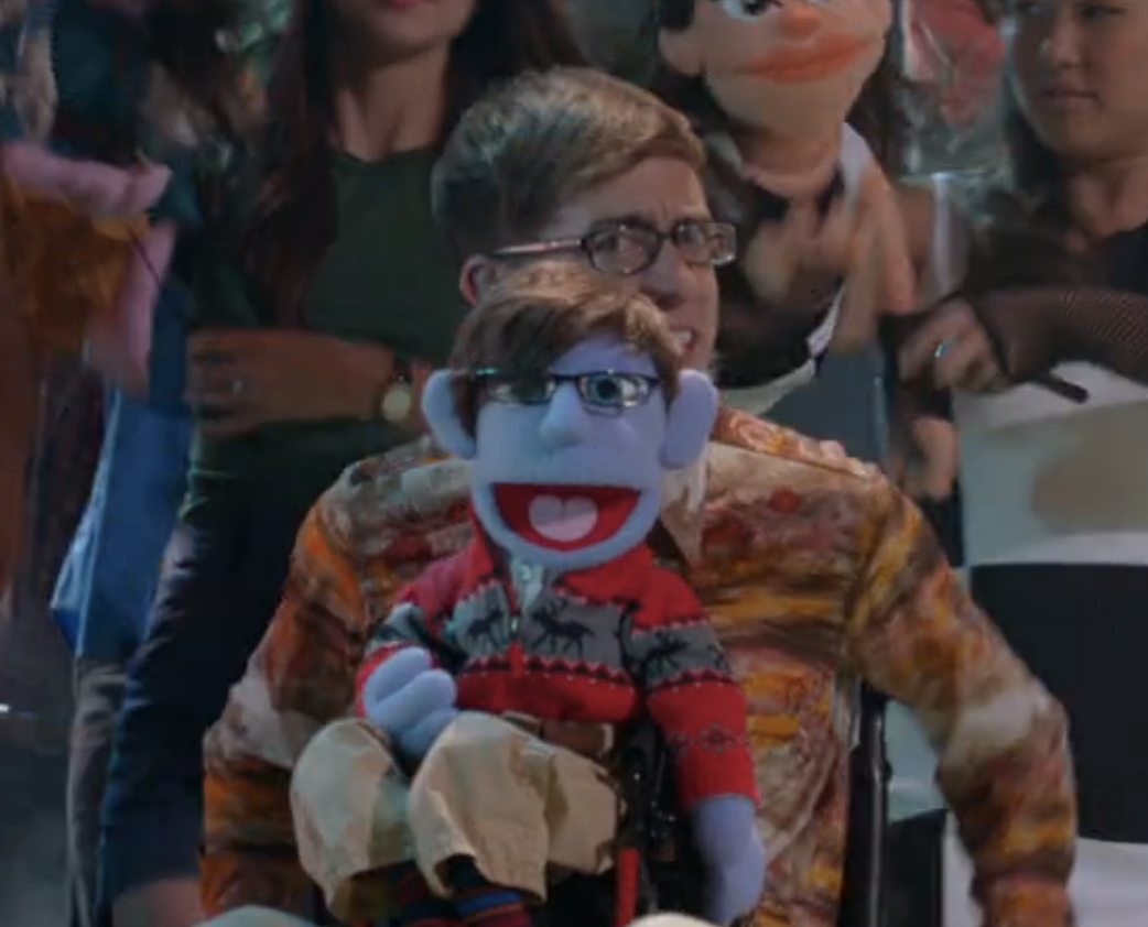 kevin&#x27;s character looking at the camera while a toy version of himself sits on his lap