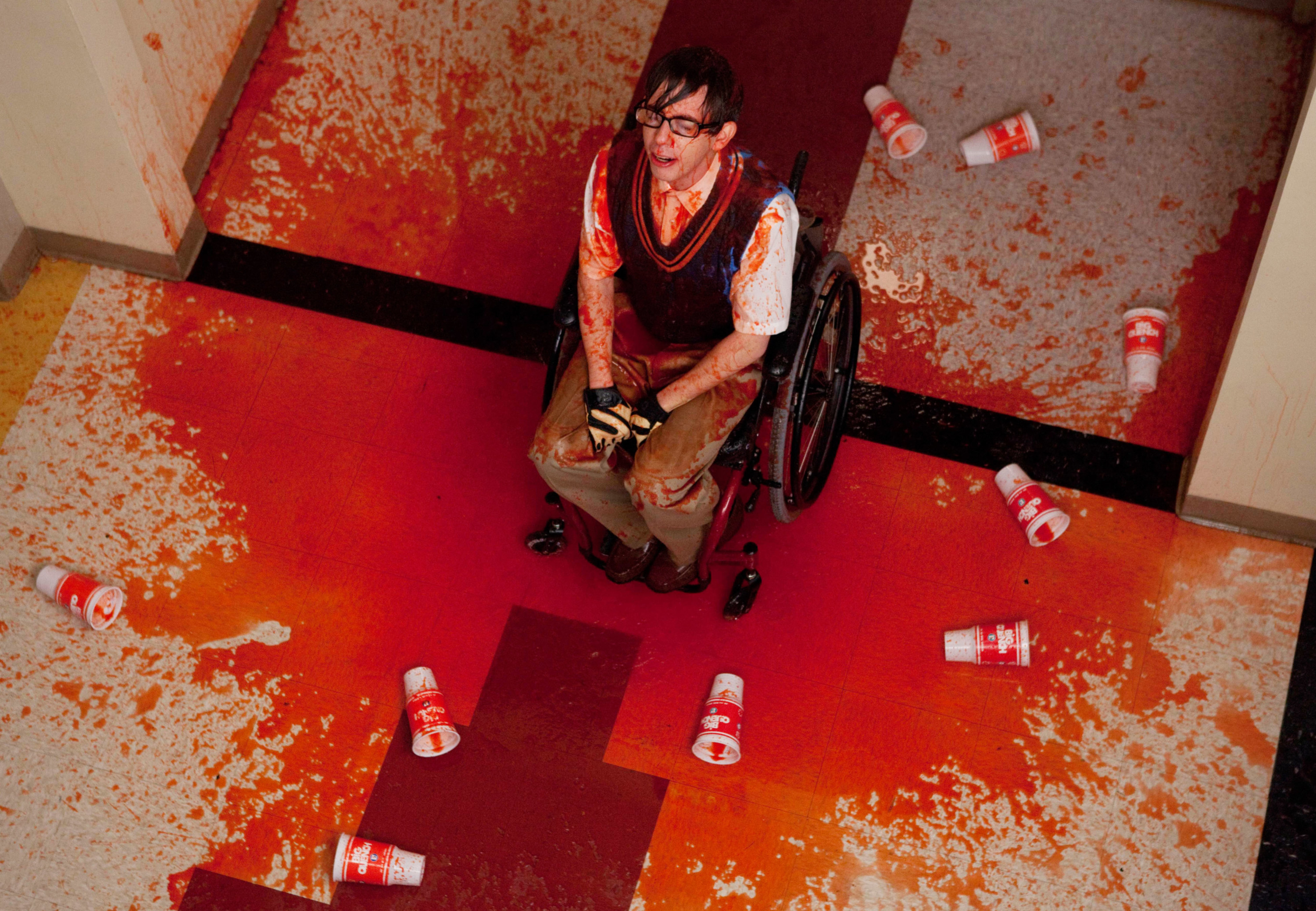 Kevin&#x27;s character sitting in the middle of the hallway with slushie all over him and the floor, empty cups lying around