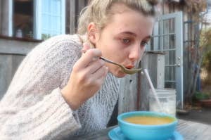 Emma Chamberlain eating soup outside