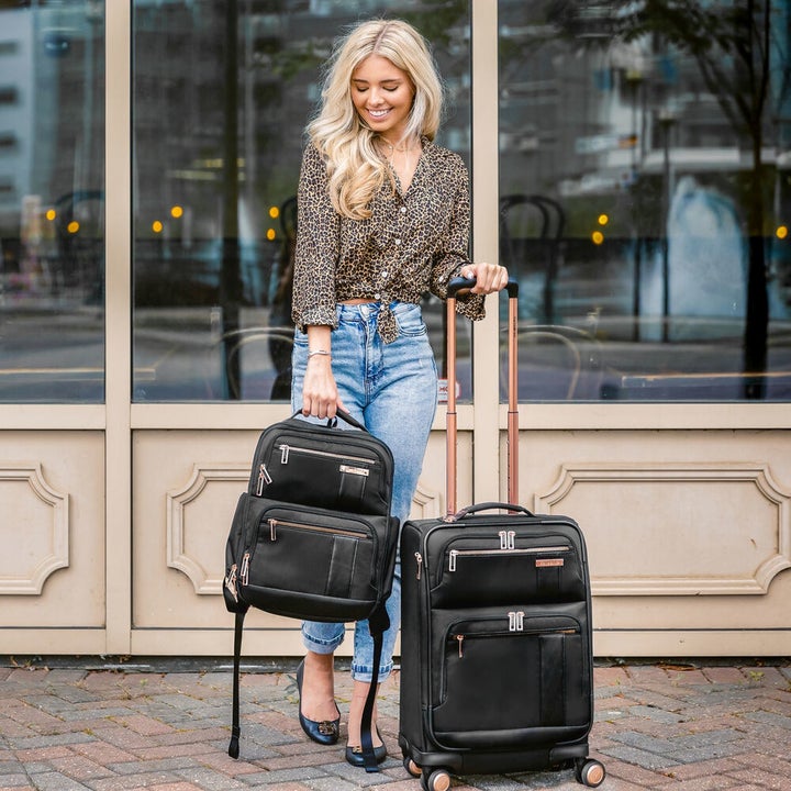 model holding a backpack and the handle of the suitcase