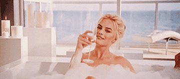 gif of Margot Robbie drinking champagne in a bath from the movie the big short.