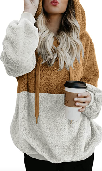 model wearing brown and white fleece pullover while holding cup of coffee