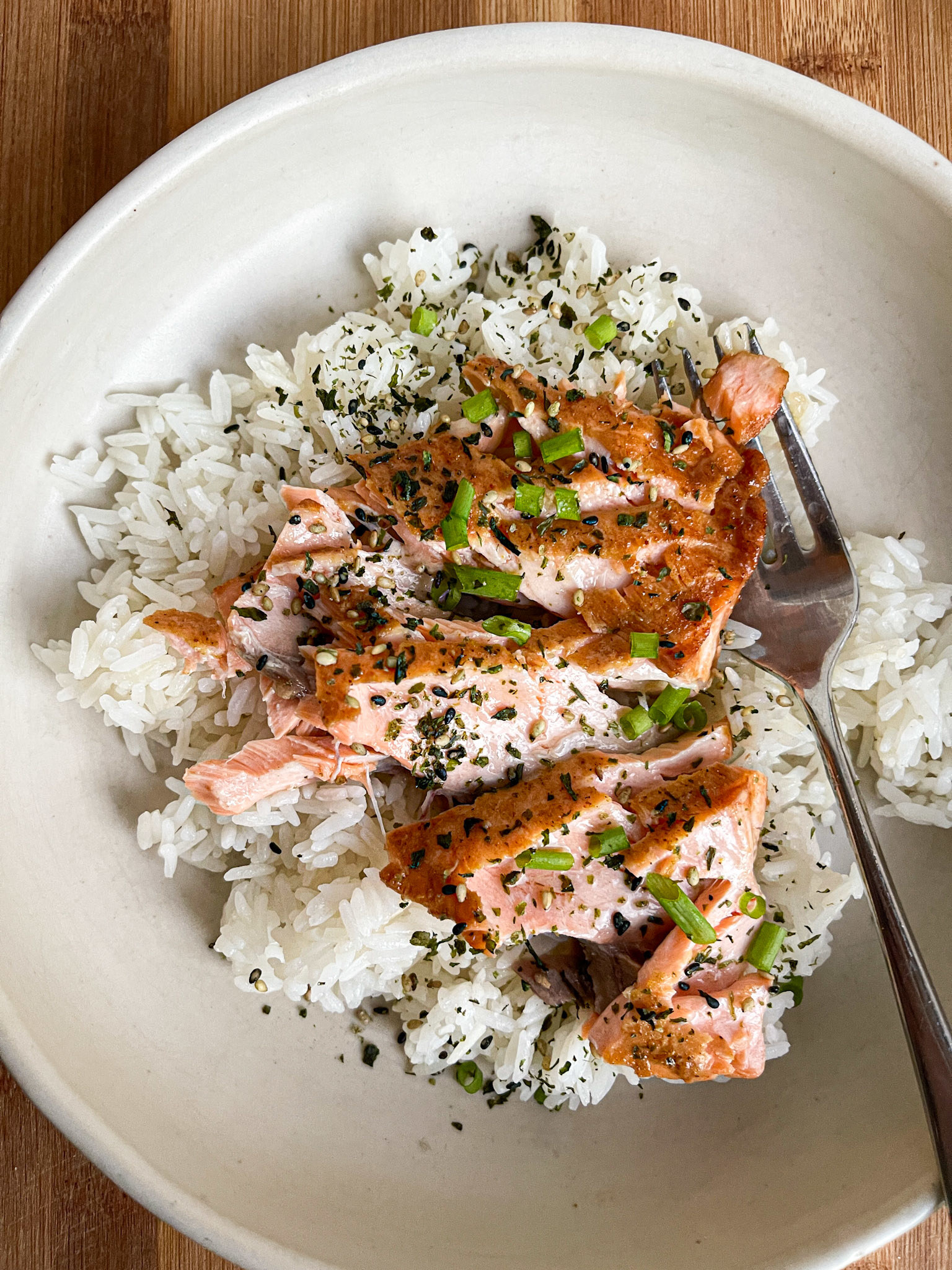 salmon with toppings over white rice in a bowl