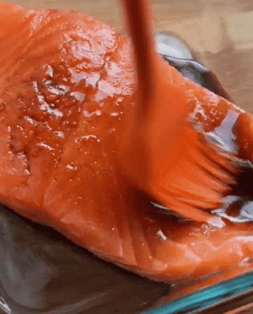 brushing sauce on raw salmon