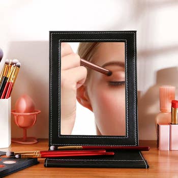Model's reflection while doing makeup in the desk mirror